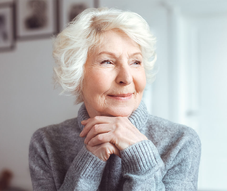 Older woman smiling as she looks out a window