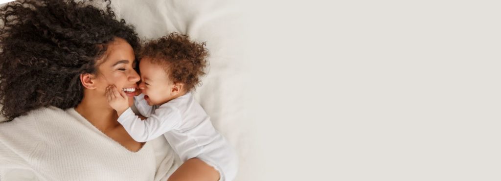woman and baby smiling laying down